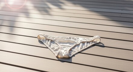 white bikini bottom lying on wooden deck in bright natural sunlight during day