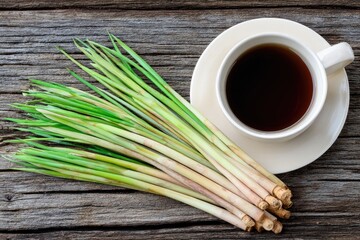 Fresh lemongrass stalks beside a cup of dark tea on a rustic wooden table