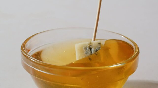 Tasty blue cheese with rosemary, honey and walnuts on white table, close up of Dorblu in cafe pouring in honey.