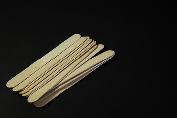 Wooden medical tongue depressors arranged on a black background—clean, clinical tools ideal for healthcare or medical-themed visuals.