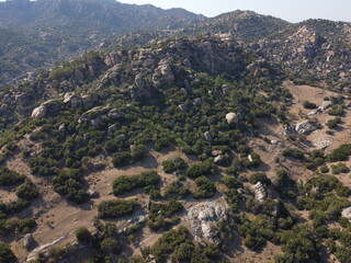 A drone view of South Türkiye's arid, Mediterranean-like hills with terra tones and sparse vegetation, captured during a scenic summer road trip
