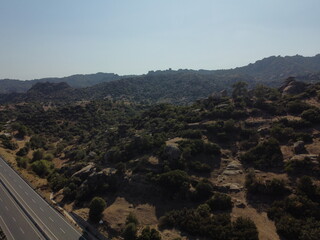 A drone view of South Türkiye's arid, Mediterranean-like hills with terra tones and sparse vegetation, captured during a scenic summer road trip