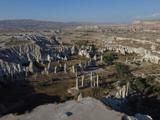 A stunning drone shot over Love Valley in Cappadocia, showcasing its iconic rock formations, surreal landscape, and warm tones under a clear sky.