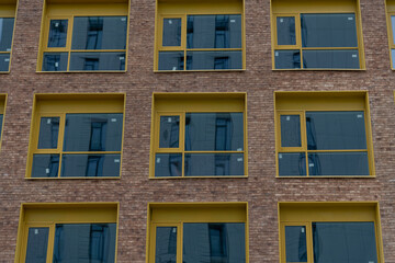 Modern building facade with yellow framed windows in an urban setting
