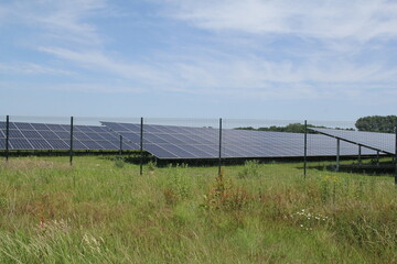 a solar park with big solar panels in the dutch countryside and a blue sky
