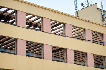Urban building undergoing structural renovation with facade partially removed and interior beams and columns fully exposed during deconstruction or reconstruction phase, stripped commercial building