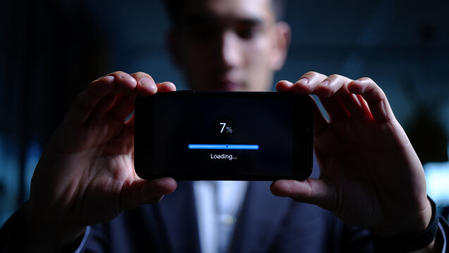 Businessman holding smartphone displaying loading progress bar indicating digital connectivity - Powered by Adobe