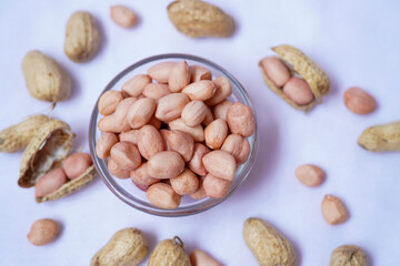 Raw Groundnuts in an glass bowl on white background. Peanuts isolated. Top angle peanuts bowl. Peanut isolated. Raw peanuts bowl.