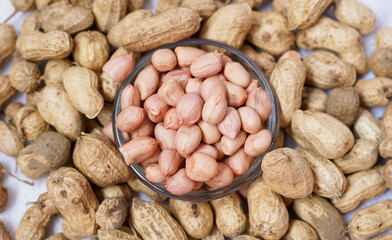 Peanut or groundnut isolated white background. Peeled peanut on peanut group on wooden bowl. Organic fresh raw food it called Arachis hypogaea on Latin name.