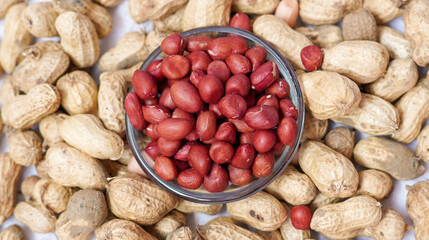 Red peanut or groundnut isolated white background. Peeled peanut on peanut group on glass bowl. Organic fresh raw food it called Arachis hypogaea on Latin name.