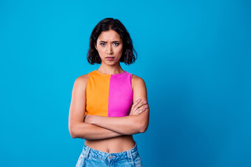 Confident brunette woman in stylish casual outfit against vibrant blue background, expressing...
