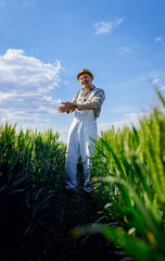 Portrait of adult male farmer standing in green wheat field looking at camera.