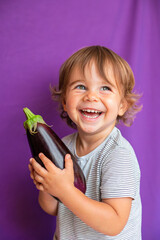 Adorable kid holding eggplant vegetable and smiling over violet studio background. Healthy relationship with food and child nutrition concept. Healthy baby food with vitamins and kids vegetarianism
