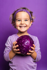 Adorable kid holding cabbage vegetable and smiling over violet studio background. Healthy relationship with food and child nutrition concept. Healthy baby food with vitamins and kids vegetarianism