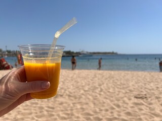 Fresh mango juice against a blurred beach and sea