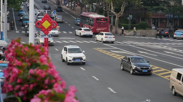 Afternoon traffic on a busy street in Qingdao, China featuring cars, taxi cabs, buses and motorbikes