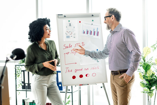 Professional business team discussing strategies and data analysis during a collaborative meeting in an executive office - Powered by Adobe