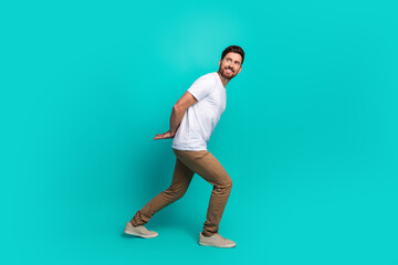 Young cheerful man posing against a turquoise background wearing a casual outfit and stylish white...