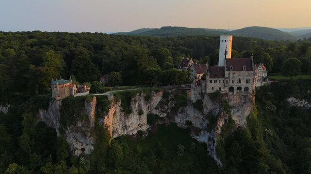 Stunning twilight drone video of Schloss Lichtenstein. Aerial view of fairy tale German castle high above Neckar tributary. Luftaufnahme Schloss Lichtenstein Wuerttemberg. Marchenschloss Wurttemberg. 