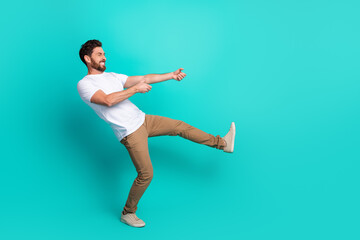 Young man showing lively gestures against turquoise background, dressed stylishly with a white...