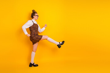 Teen girl woman in a plaid dress and glasses posing against a bright yellow background, expressive...