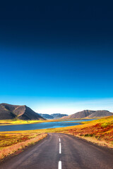 Cover page with a paved road, Ring road, through rough and colorful Icelandic landscape, Iceland, summer, suny blue sky, copy space