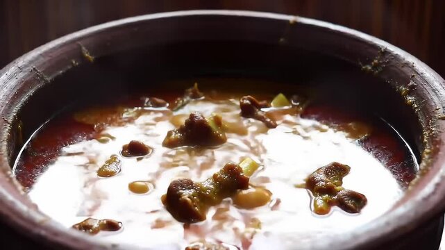 A rich, hearty stew simmers in a terracotta pot, filled with meat and vegetables