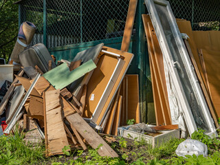 Pile of discarded wood, boards and construction debris in backyard, ready for disposal or...