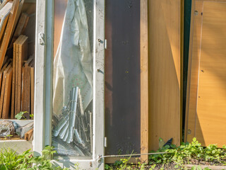 Close-up of discarded furniture panels and window parts outdoors. DIY renovation debris and old...
