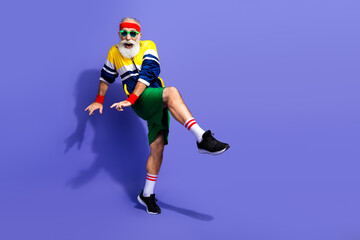 Funny man in retro sports attire energetically posing against a purple background, showcasing vintage style and active lifestyle