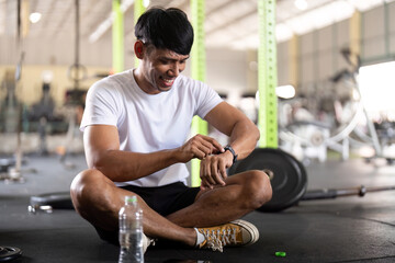 Fitness and Wellness. Young man checking smartwatch after workout in gym.