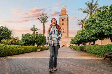 Young woman tourist walking in the Koutoubia Mosque gardens at sunset in Marrakech, Morocco, enjoying her trip