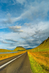 Cover page with a paved road, Ring road, through rough and colorful Icelandic landscape, Iceland, summer, suny blue sky, copy space
