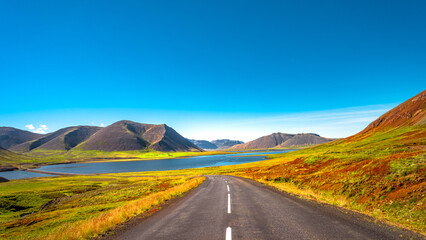 Panorama with a paved road, Ring road, through rough and colorful Icelandic landscape, Iceland, summer, suny blue sky