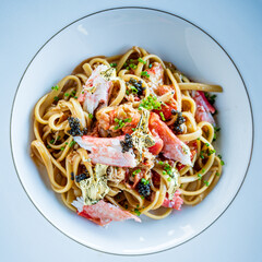 A rich bowl of linguine topped with fresh crab, caviar, and delicate garnishes awaits!