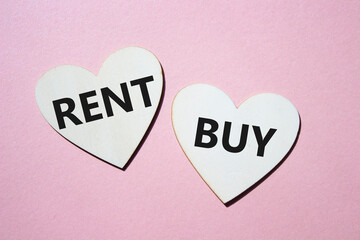 Rent or Buy symbol. Concept word Rent or Buy on wooden hearts. Beautiful pink background. Business and Rent or Buy concept. Copy space