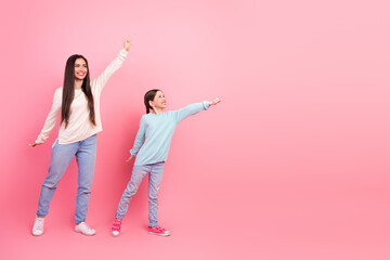 Mother and daughter showing superhero poses on a pink background, expressing joy, family bonding, and positive energy