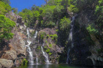 Obraz premium waterfall cascading down rocky cliffs into a pool