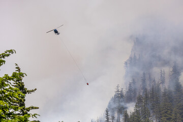 Helicopter Fighting a Forest Fire Amidst Smoke in Squamish, BC, Canada
