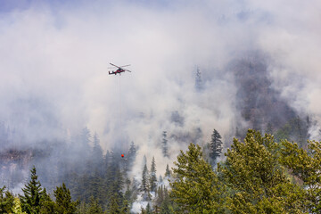 Obraz premium Helicopter Battling Forest Fire Amid Dense Smoke in Squamish, BC, Canada