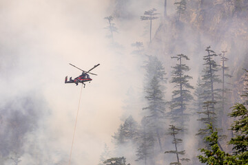 Helicopter Battling Forest Fire Amid Smoke in Squamish, BC, Canada