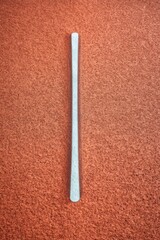 White Vertical Stick on Red Running Track Surface