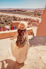 Tourist with backpack and hat walking in Ait Benhaddou, Morocco, admiring the landscape