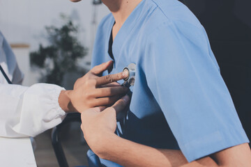 A physician uses a stethoscope to examine a patient's heart during a clinic appointment.