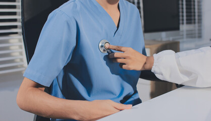 A physician uses a stethoscope to examine a patient's heart during a clinic appointment.