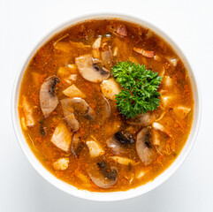 A flavorful bowl of hearty soup brimming with mushrooms and vegetables garnished with fresh herbs