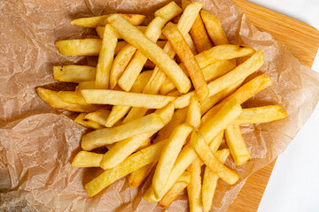 Golden crispy fries piled on parchment paper evoke warmth and comfort, perfect for sharing