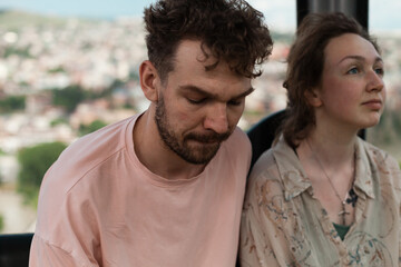 Obraz premium A couple rides a cable car over the city center of Tbilisi, enjoying panoramic views of rooftops and landmarks in summer afternoon