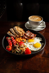 A filling breakfast of eggs, bacon, sausages, baked beans, toast, and coffee