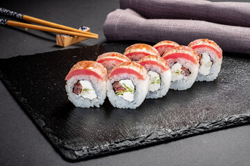 Vibrant sushi rolls displayed on a dark slate, highlighting their colorful toppings and fillings